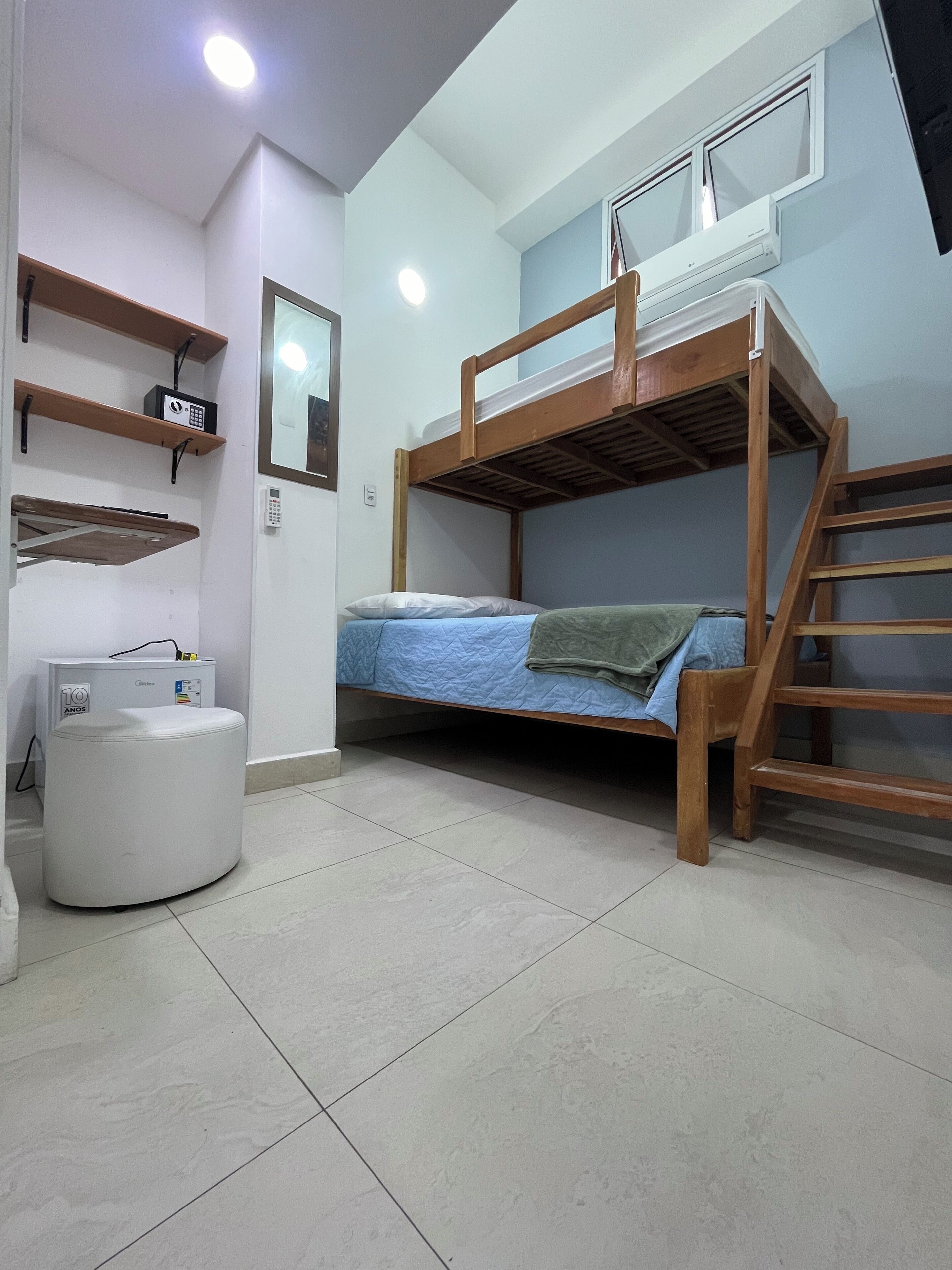 A bunk bed room with a desk, shelves, and a radiator.
