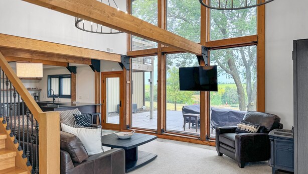 A spacious living area with a staircase, a large TV, and a view of the outdoors.