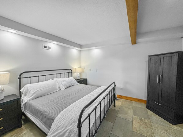 Un dormitorio con cama, mesitas de noche, armario y una pequeña mesa auxiliar.