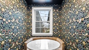 Une pièce avec une table ronde et un banc, le tout entouré d’un papier peint à motifs floraux.