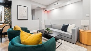 Un salon moderne avec un canapé gris, des fauteuils turquoise et une table basse noire.