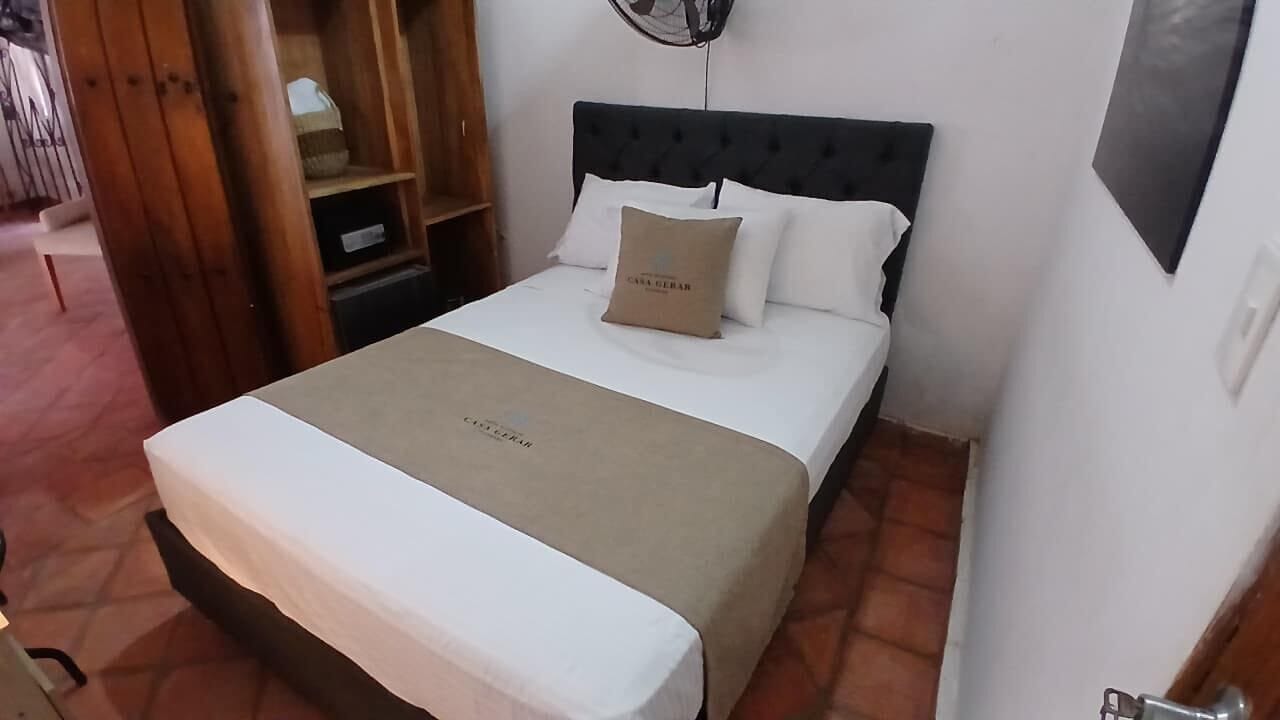 A neatly made bed with a white and beige bedspread, a pillow with text, and a headboard.