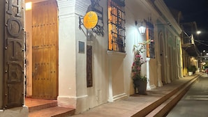 Une vue de rue d’un bâtiment avec une porte en bois et une enseigne sur laquelle on peut lire « TIENDA CAFE ABRAHAM ».