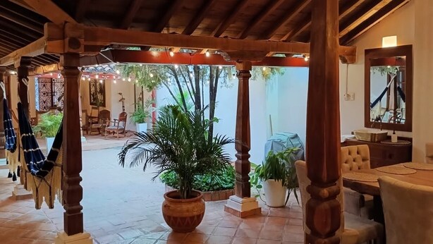 Un patio couvert agrémenté de piliers en bois, de carreaux de terre cuite et de plantes en pot.