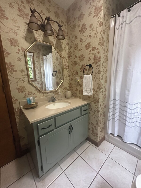 Un baño con lavamanos, espejo y cortina de ducha.