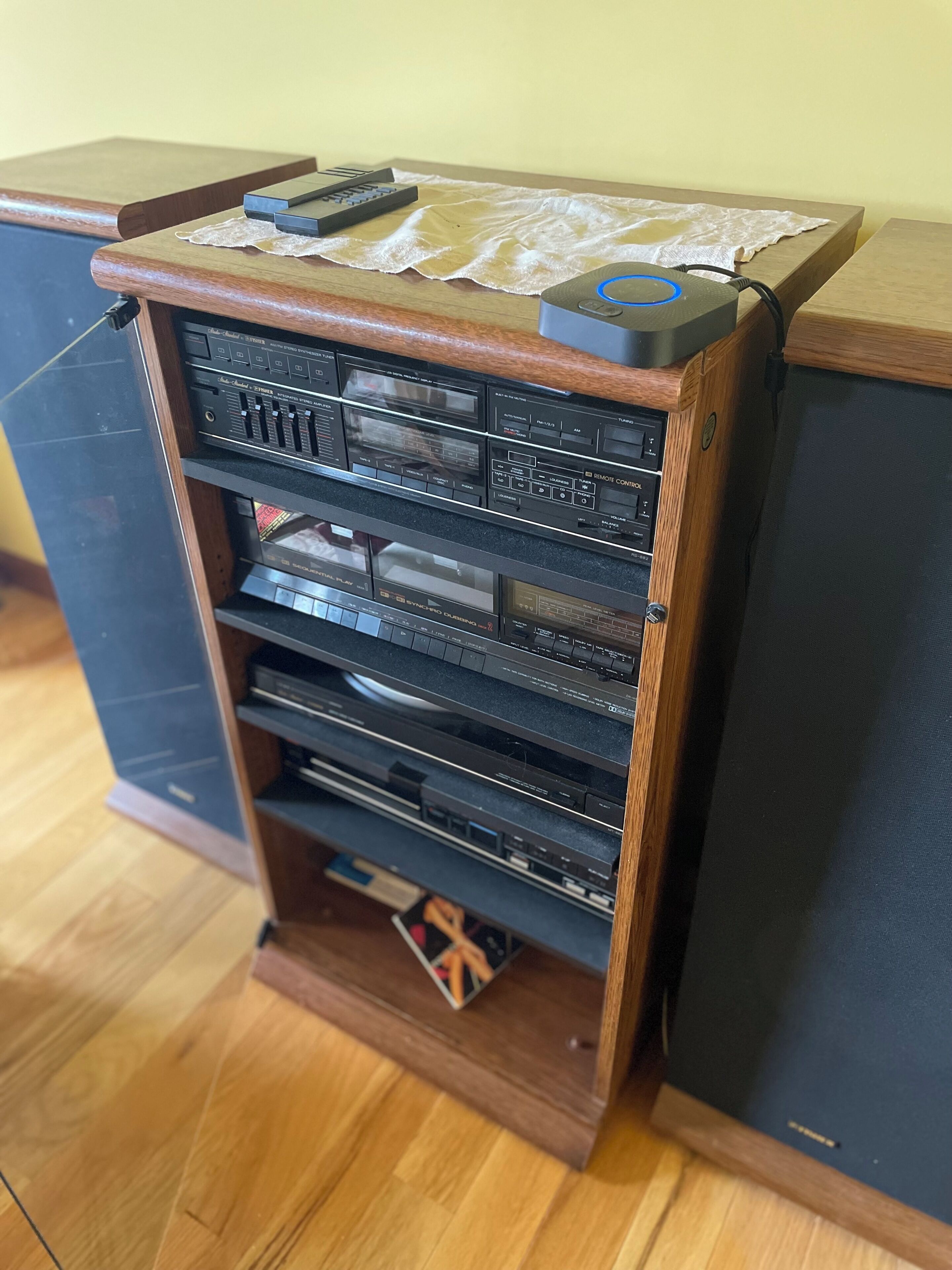 A wooden entertainment center with multiple shelves containing various electronic devices.