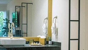 Un baño moderno con un espejo grande, un lavamanos redondo y un banco de madera.