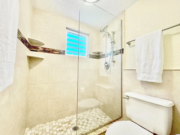 Un baño con ducha de vidrio, inodoro y perchero para toallas.