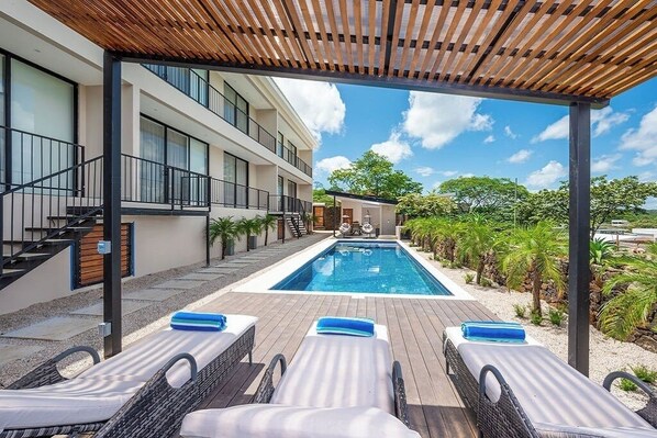 A poolside area with lounge chairs and a wooden pergola.