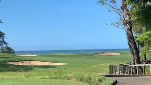 En golfbana med bunkrar och fri utsikt över havet.