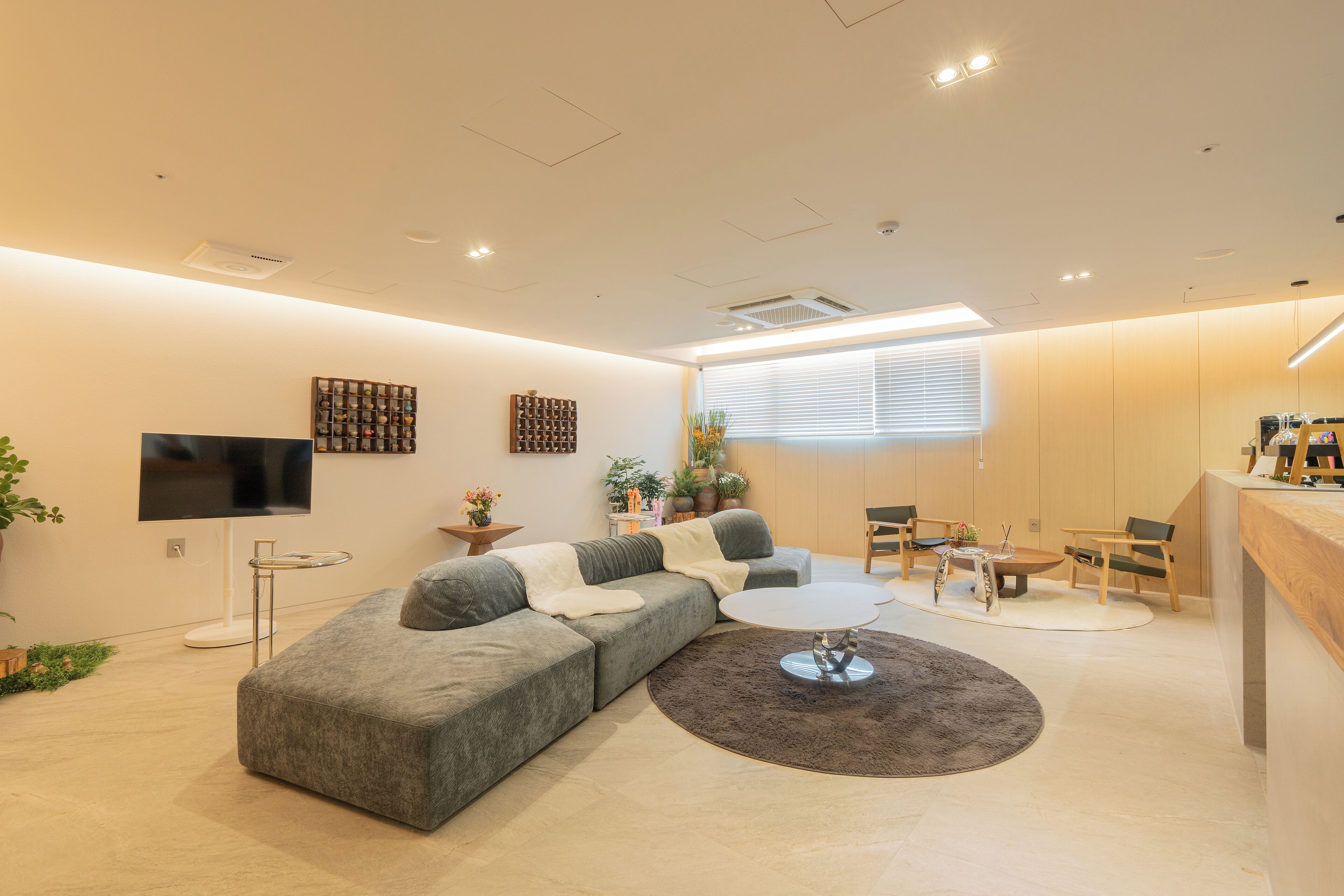 Una sala moderna con un sofá modular, una mesa de centro redonda y un televisor montado en la pared.