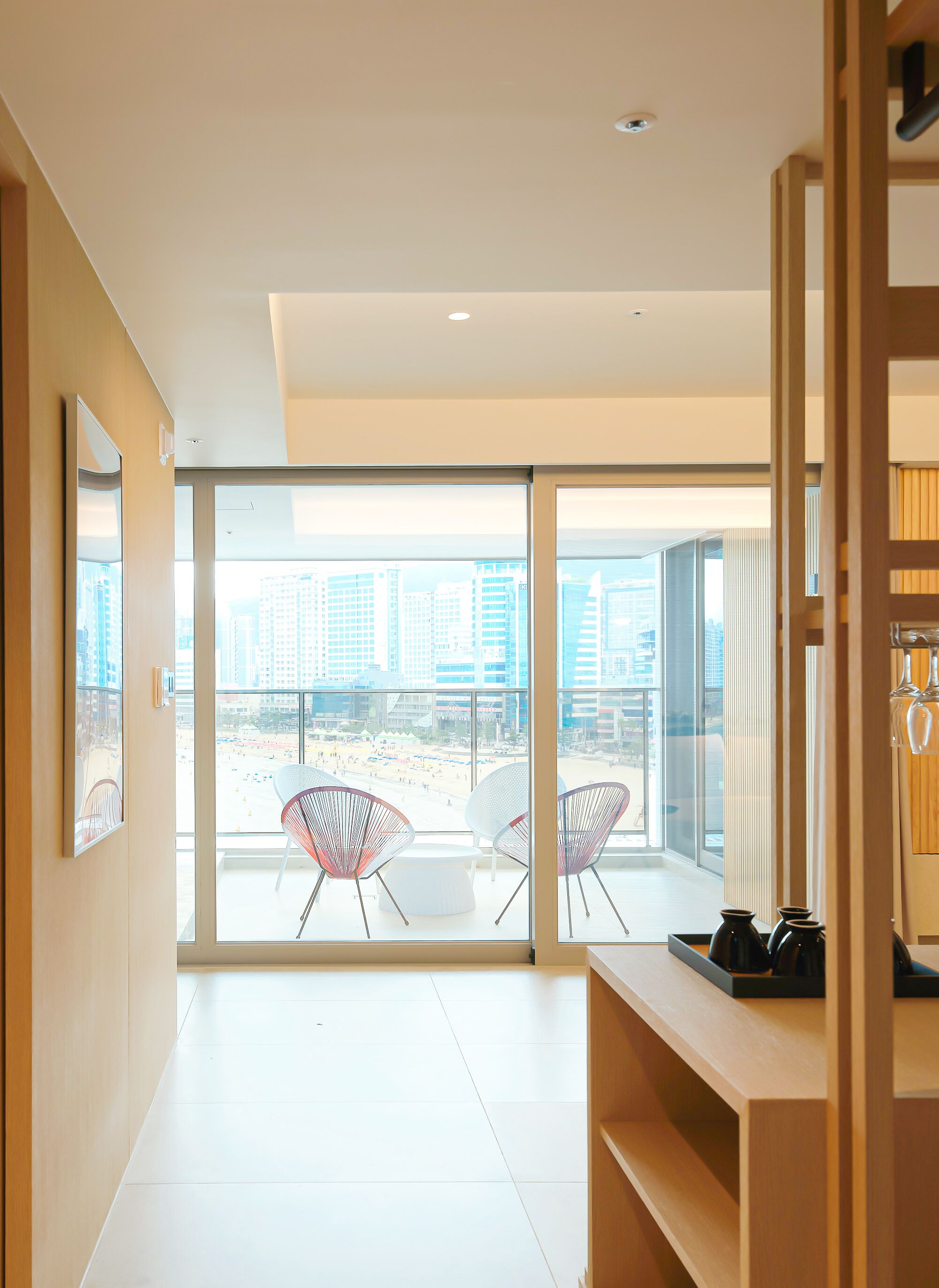 A modern interior with a large glass door leading to a balcony with beach views.