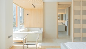 Una habitación de hotel moderna con una bañera grande, zona de ducha separada y vestidor.