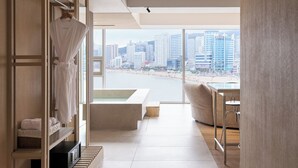 Habitación de hotel moderna con vistas a la ciudad, un ventanal grande y un diseño minimalista.