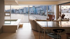Una sala de estar moderna con un amplio ventanal que ofrece vistas a la playa y al paisaje urbano.