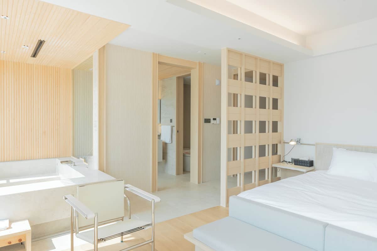 Una habitación de hotel moderna con una cama grande, un baño con bañera y un vestidor.