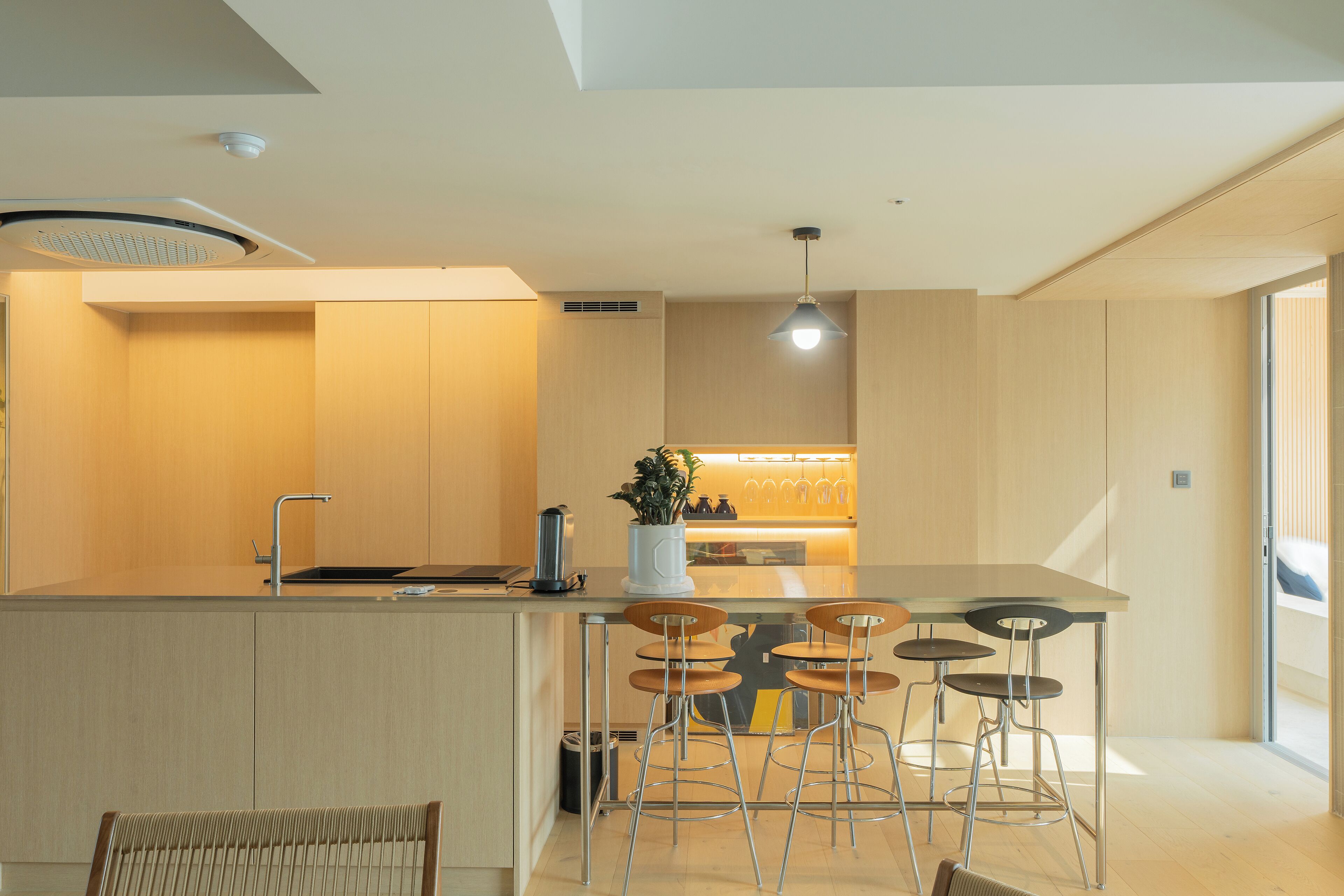 A modern kitchen with a central island, bar stools, and a built-in sink.