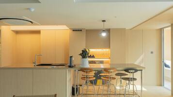 A modern kitchen with a central island, bar stools, and a built-in sink.