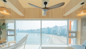 Una habitación moderna con un ventanal grande, una hamaca, un sofá y un ventilador de techo.