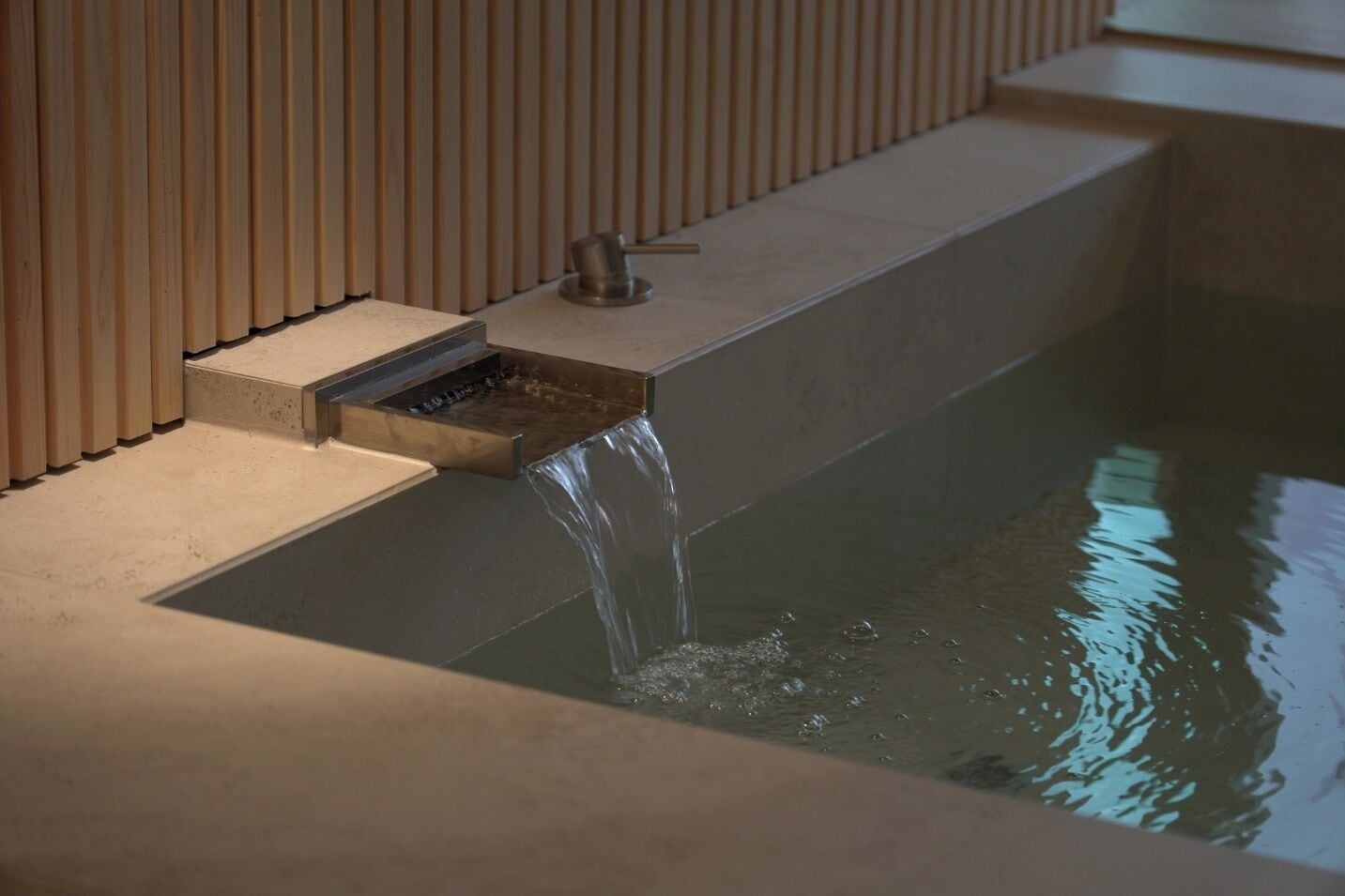 A modern bathroom with a built-in sink and a water feature.
