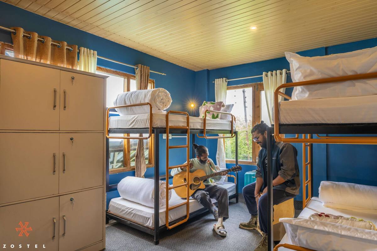 Ein Schlafsaalzimmer mit Etagenbetten, einem Kleiderschrank und einem Fenster mit Vorhängen.