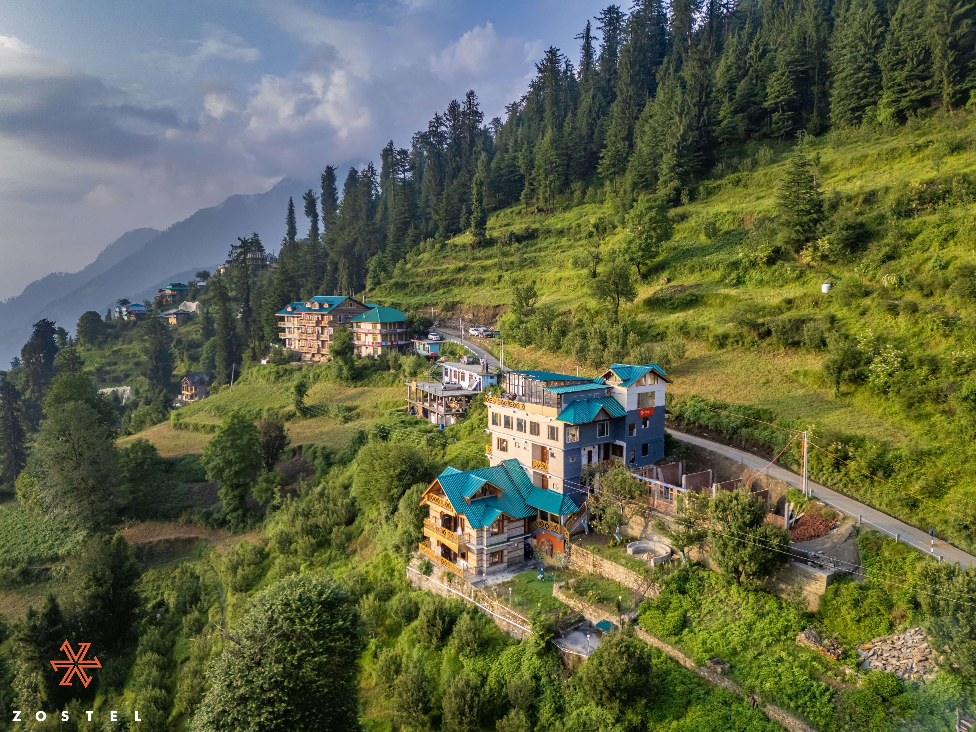 A hillside with multiple buildings, including a prominent hotel with a green roof and a balcony.