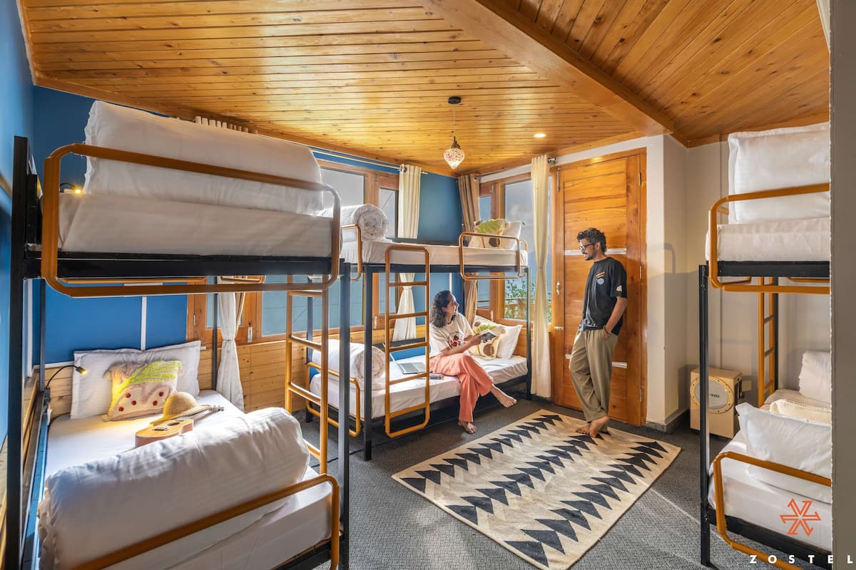 Ein Schlafsaalzimmer mit Etagenbetten, einer Holzbalkendecke und einem großen Fenster.