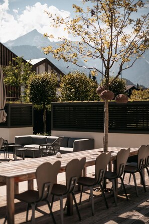 An outdoor seating area with a wooden table and chairs, a sofa, and a small round table. - aja Garmisch-partenkirchen (Garmisch-Partenkirchen)