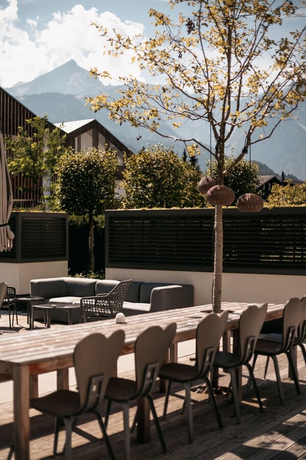 An outdoor seating area with a wooden table and chairs, a sofa, and a small round table.