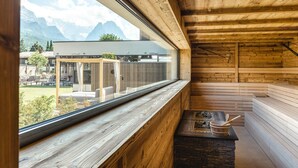 A wooden cabin with a large window overlooking a mountain landscape. Inside, there is a stone fireplace with a wooden bowl and spoon. - aja Garmisch-partenkirchen (Garmisch-Partenkirchen)