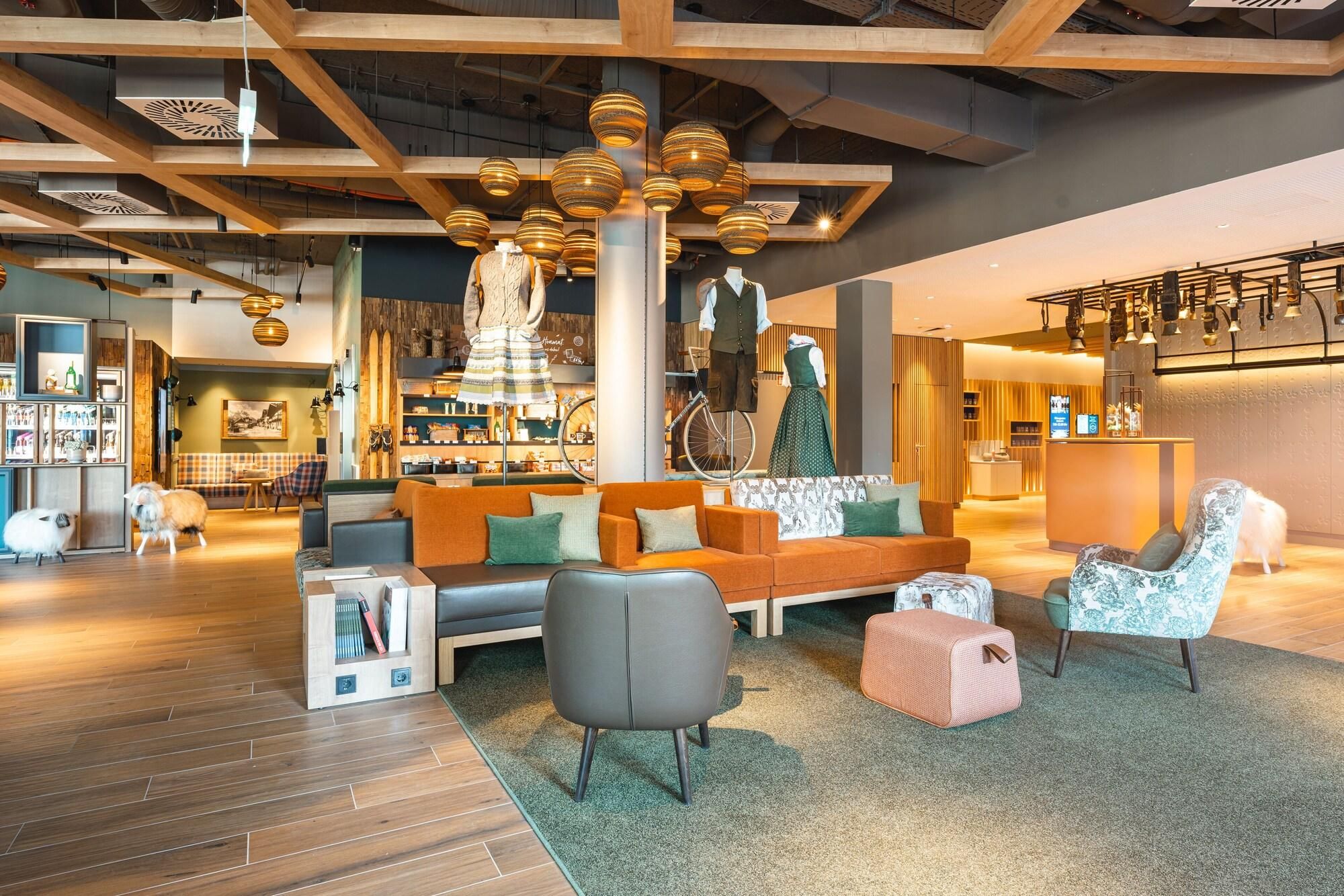 Ein modernes Interieur mit Holzbalkendecke, einer Sitzecke mit Sofa und Sesseln sowie einem Empfangstresen.