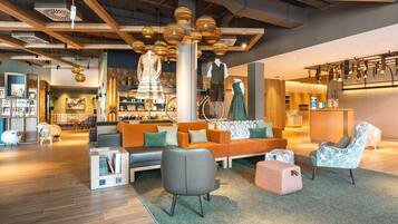 Ein modernes Interieur mit Holzbalkendecke, einer Sitzecke mit Sofa und Sesseln sowie einem Empfangstresen.