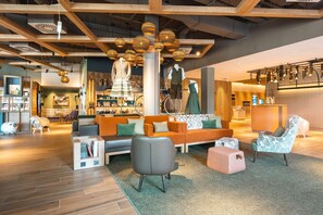 A modern interior with a wooden ceiling, a seating area with a sofa and chairs, and a reception desk. - aja Garmisch-partenkirchen (Garmisch-Partenkirchen)
