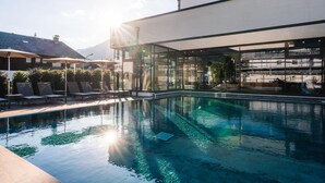 Un espace piscine moderne avec une eau cristalline, des chaises longues et un bâtiment entièrement vitré.