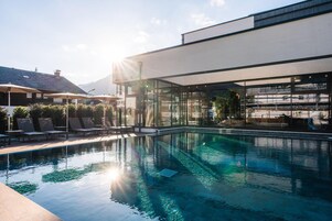 Un espace piscine moderne avec une eau cristalline, des chaises longues et un bâtiment entièrement vitré.