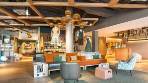A modern interior with a wooden ceiling, a seating area with a sofa and chairs, and a reception desk. - aja Garmisch-partenkirchen (Garmisch-Partenkirchen)