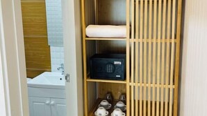 Ein Holzregal mit einem Radio, einem gefalteten Handtuch und gestapelten Tassen in einem Badezimmer.