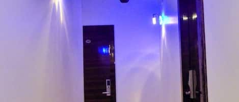 A hallway with a wooden ceiling, recessed lighting, and a door at the end.