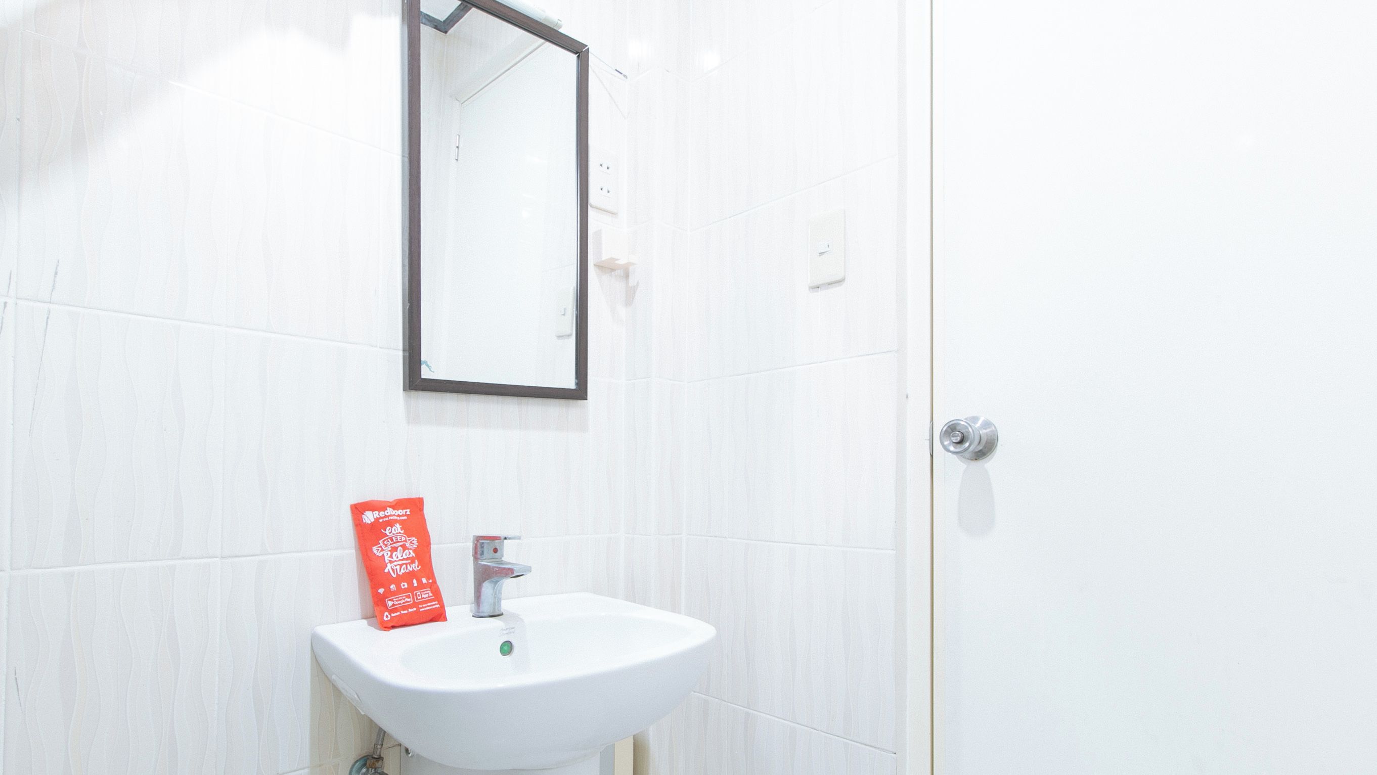 A bathroom with a white sink, a mirror, and a door.