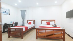 A hotel room with two wooden beds, a desk, a chair, a television, and a window with curtains. - Reddoorz @ Rj's Bldg Near Lyceum Gen. Trias Cavite (General Trias)
