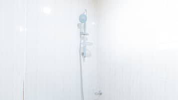 A shower with a handheld showerhead and a wall-mounted faucet.
