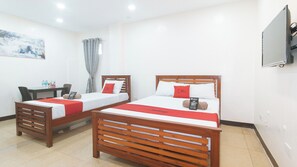 A hotel room with two wooden beds, a desk, and a TV. - Reddoorz @ Rj's Bldg Near Lyceum Gen. Trias Cavite (General Trias)