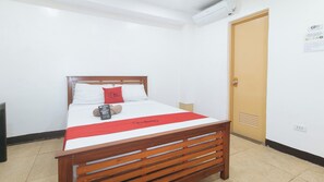 A single bed with a wooden headboard, a red and white bedspread, and a red pillow with the text "Red Door." - Reddoorz @ Rj's Bldg Near Lyceum Gen. Trias Cavite (General Trias)