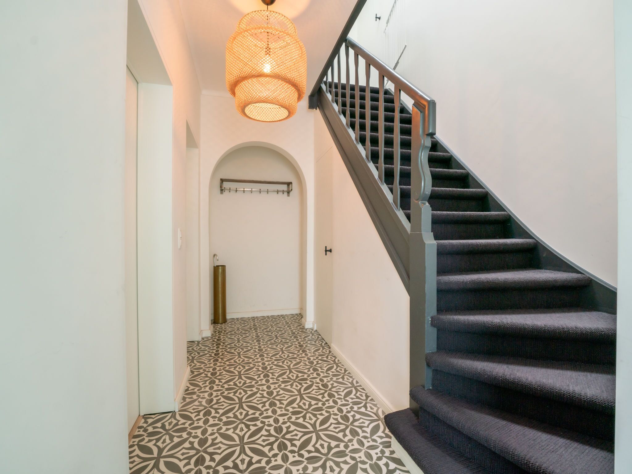 Una escalera con alfombra estampada y una lámpara colgante.