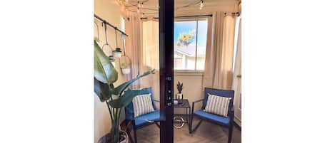 A cozy room with two blue chairs, a large potted plant, and a small table.