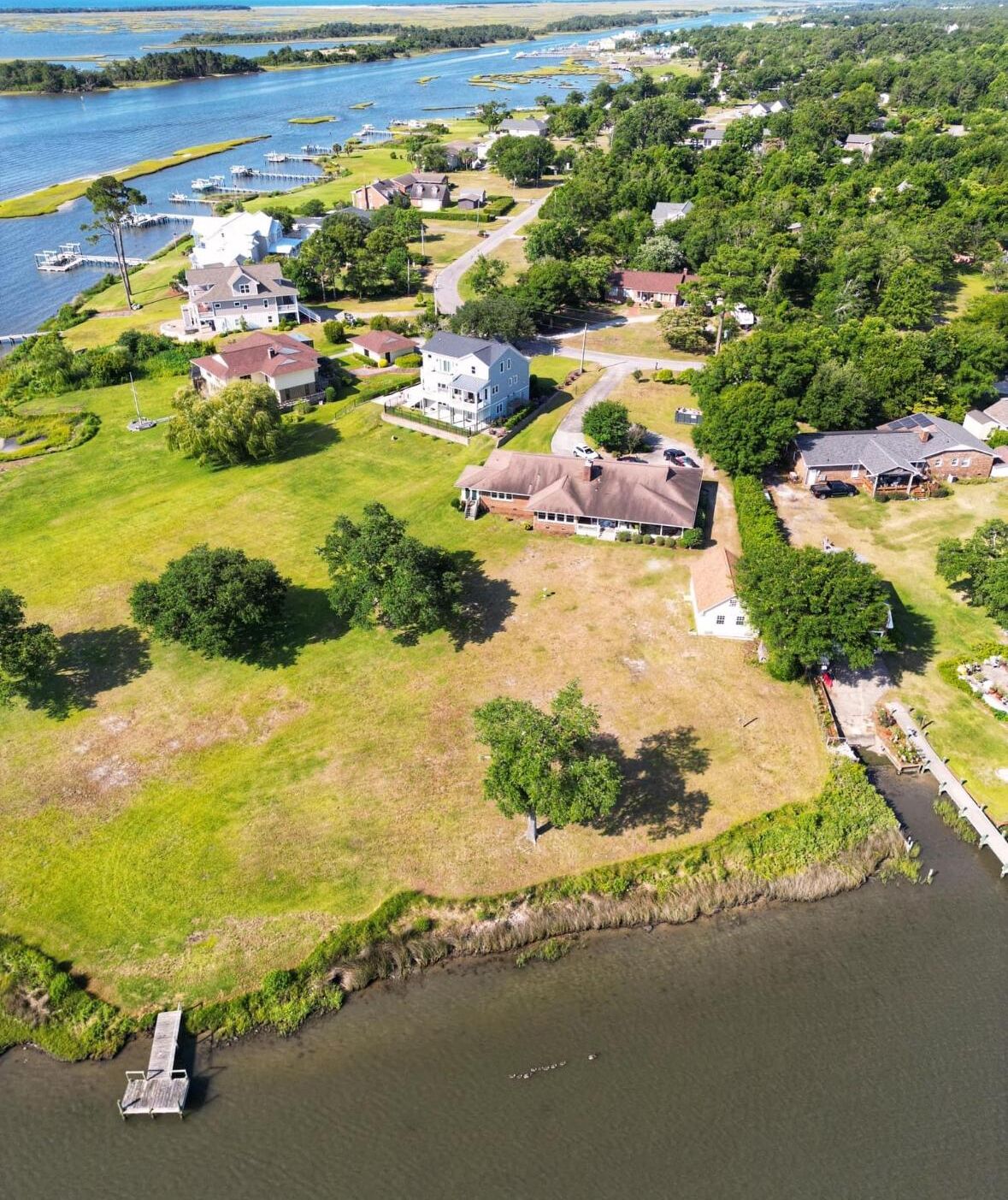 An aerial view of a residential area with houses, a dock, and a river.