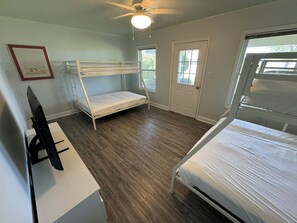 A room with two bunk beds, a desk with a computer, a ceiling fan, and a window. - Stunning waterfront views; 4-bedroom house directly on Intracoastal waterway! (Hubert)