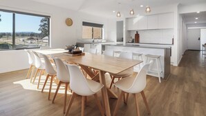 Una cucina moderna con isola centrale, mobili bianchi e un'ampia finestra che dà su una strada.