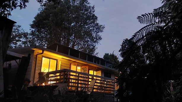 Un bâtiment moderne doté de grandes fenêtres et d’un balcon, entouré d’arbres.
