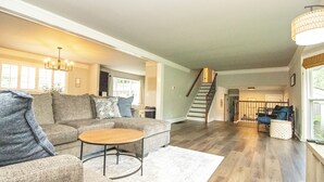 A spacious living room with a grey sofa, a coffee table, and a staircase leading to another level.